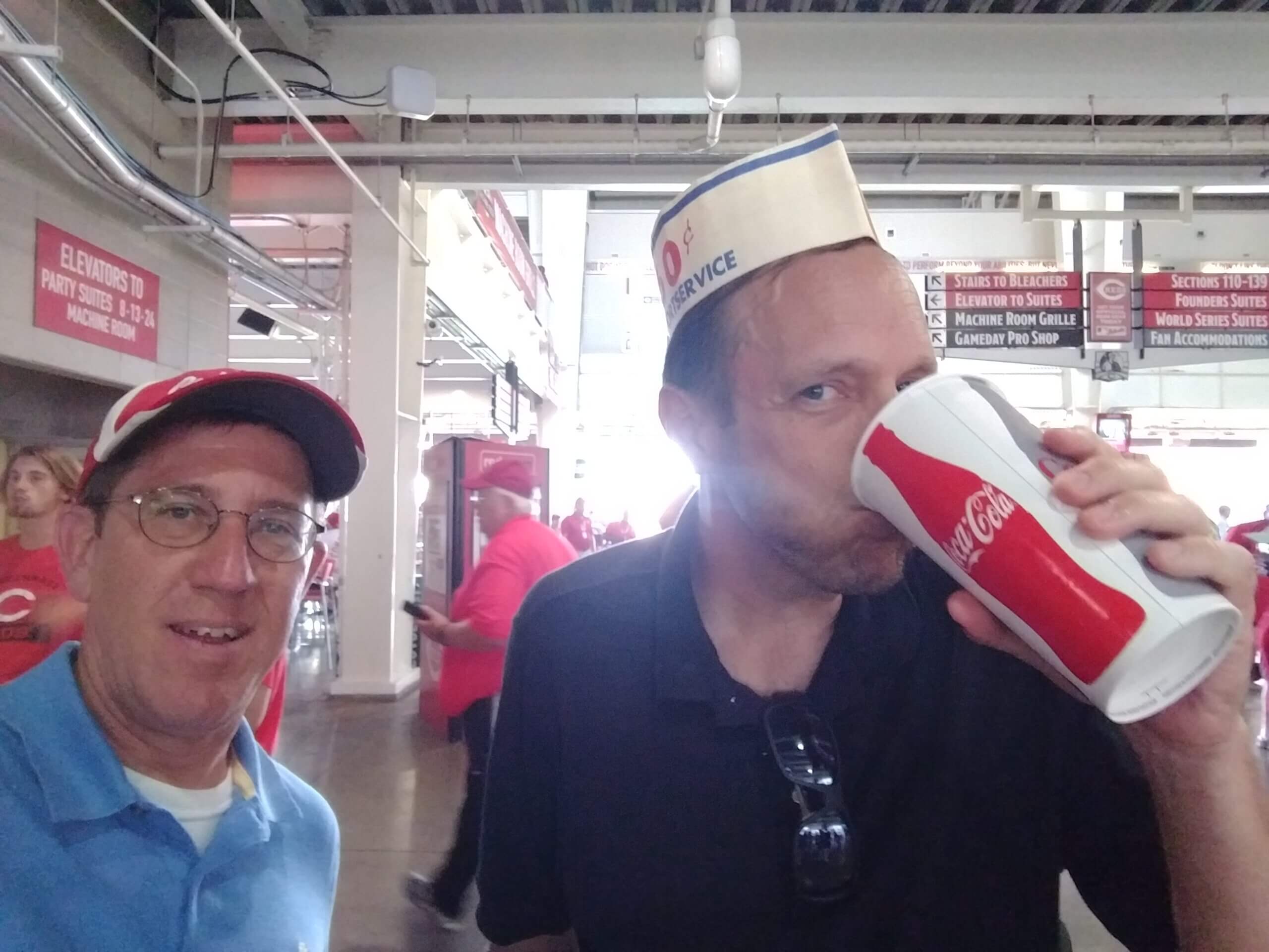 Two enthusiastic baseball fans enjoying a cold Coca Cola for a temporary refreshment.